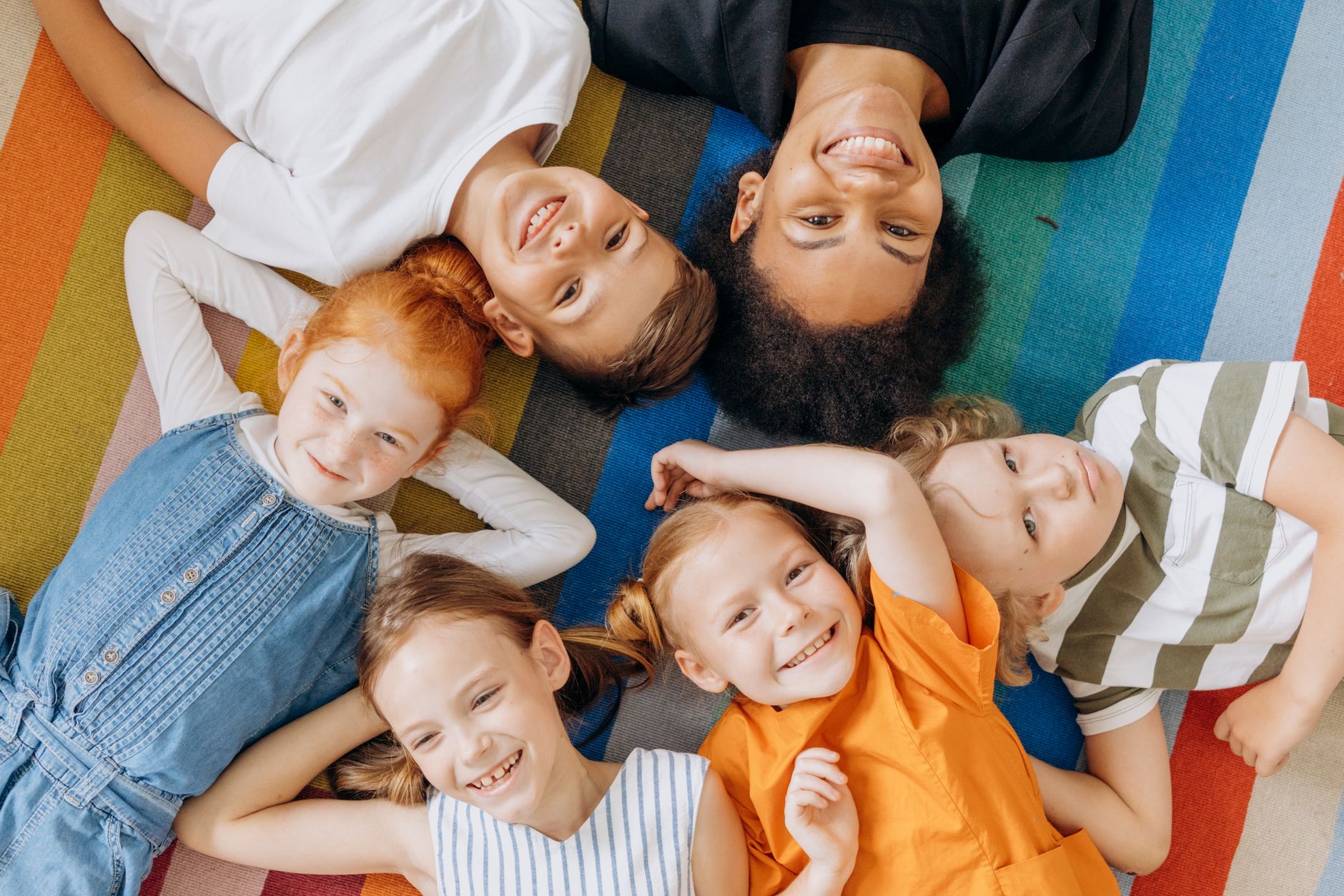 kids lying on colorful rug